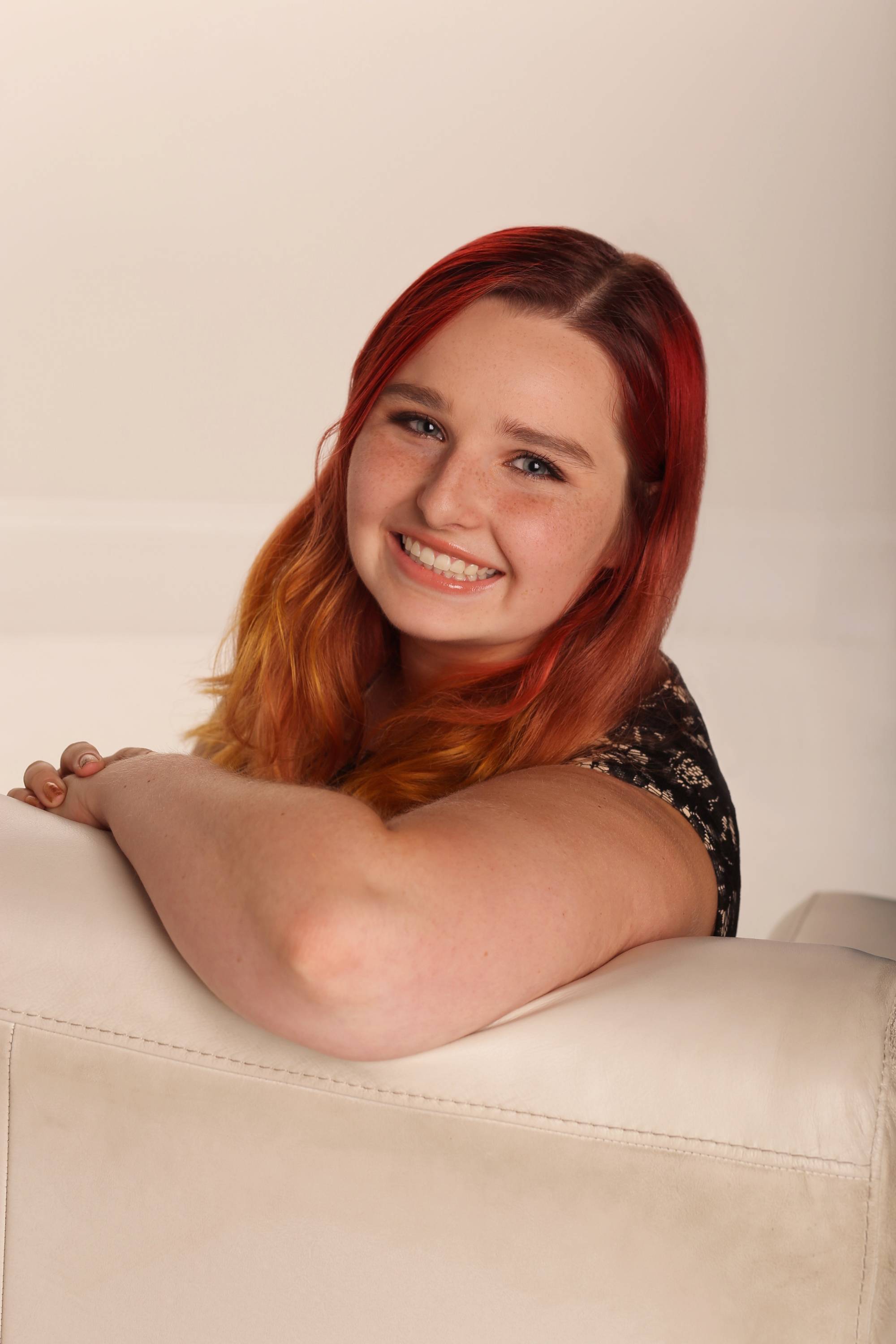 Woman smiling, turned on couch to face camera